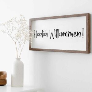 Mit der Schablone Herzlich Willkommen wurde ein Farmhouse-Schild gestaltet. Dieses Schild hat einen Holzrahmen und hängt an der Wand.